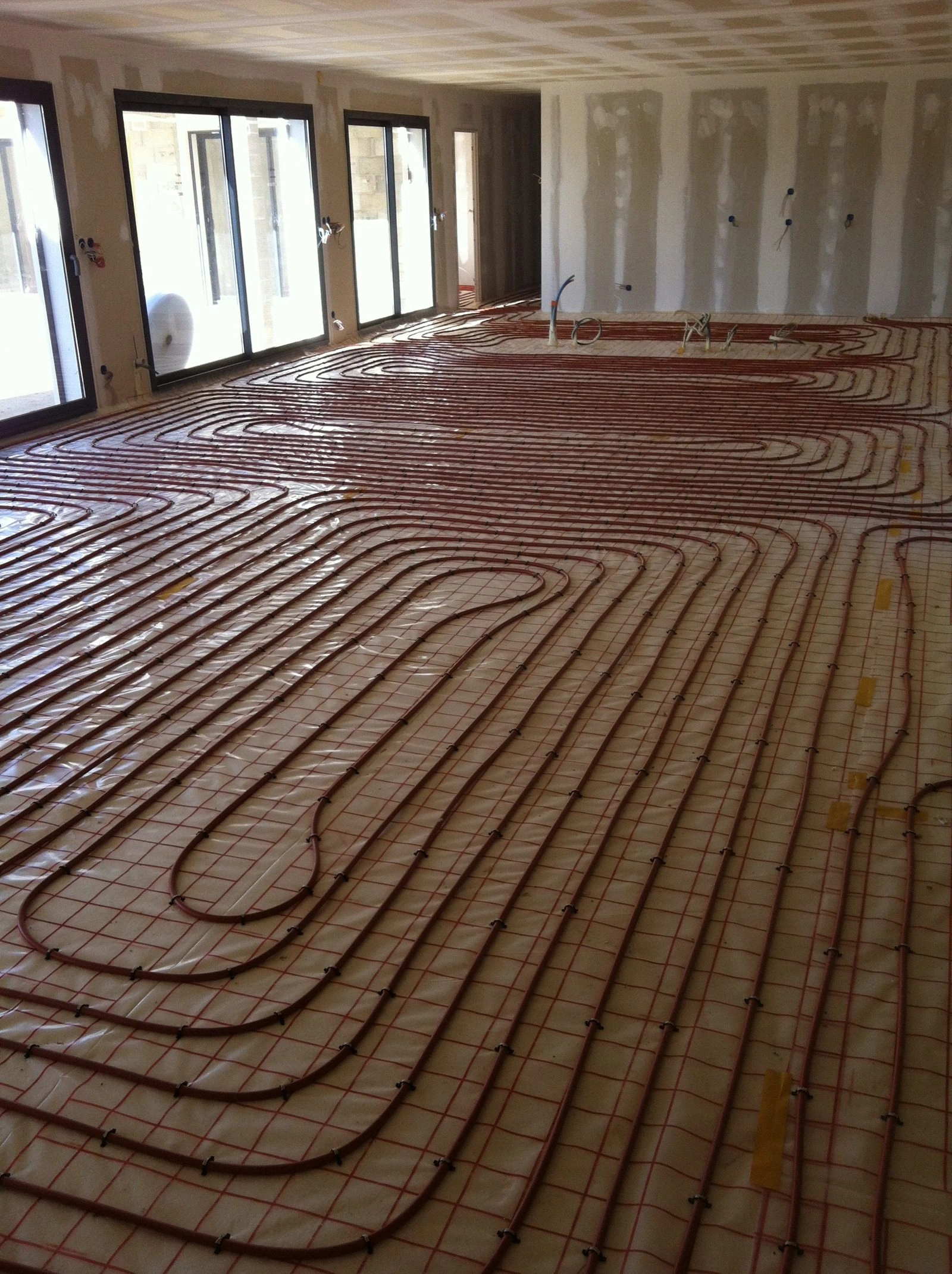 Tubes de plancher chauffant posés à nu sur leur isolant, avant coulage de la chape fluide, chantier dans le Gard Tubes de plancher chauffant posés à nu sur leur isolant, avant coulage de la chape fluide, chantier dans le Gard